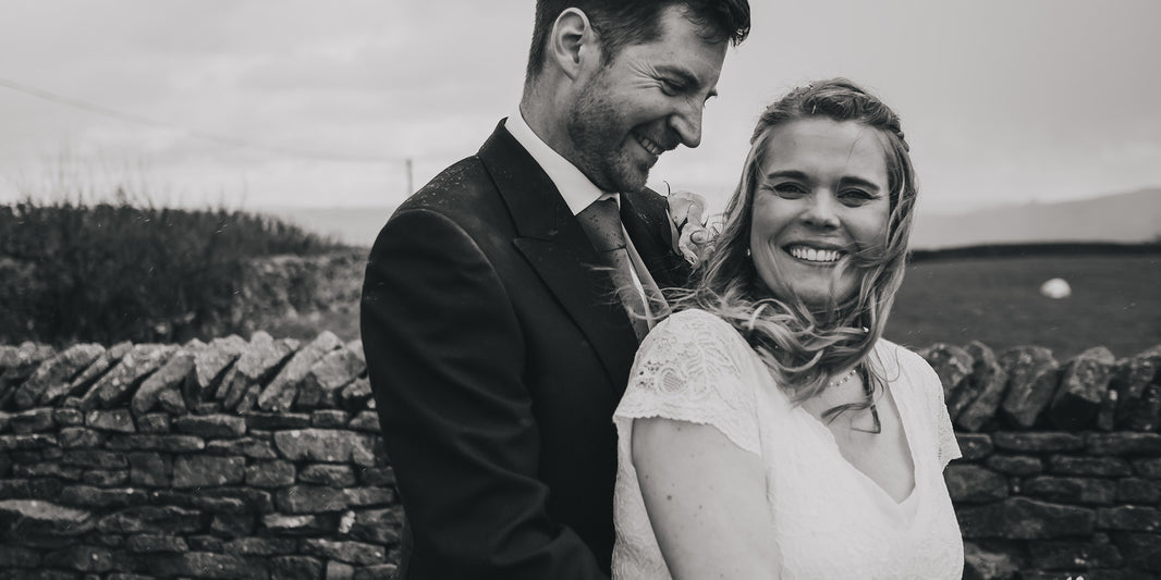 Black and white photo of groom and bride in front of dry stone wall in Yorkshire