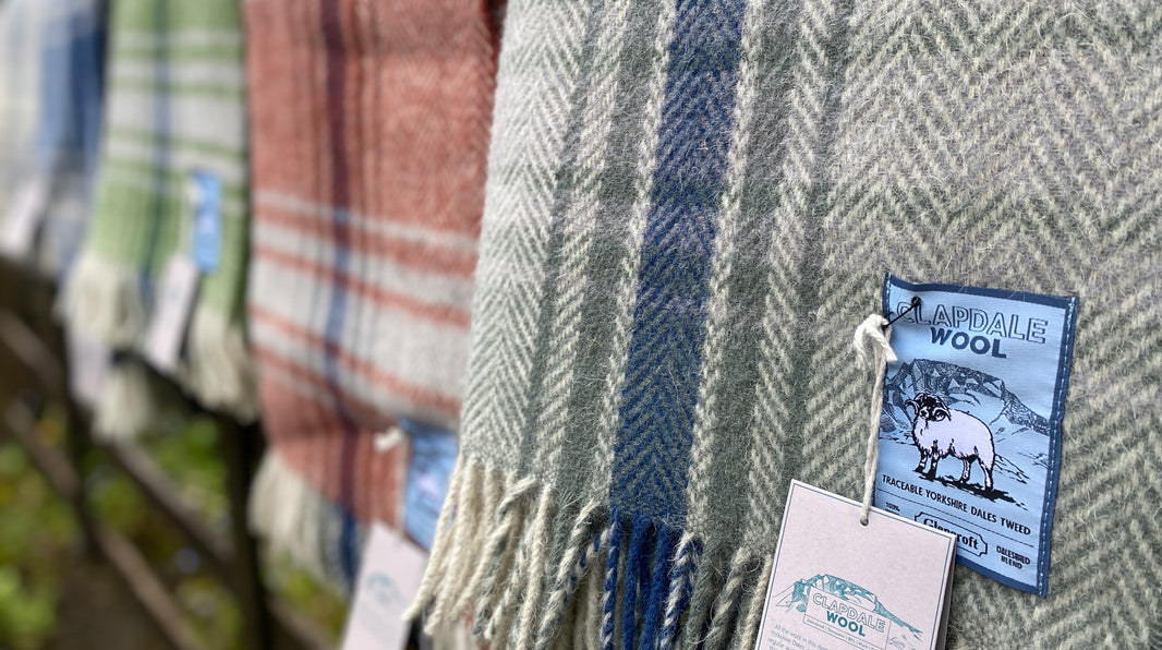 Close up of grey and blue plaid wool travel rug showing label and other rugs in background