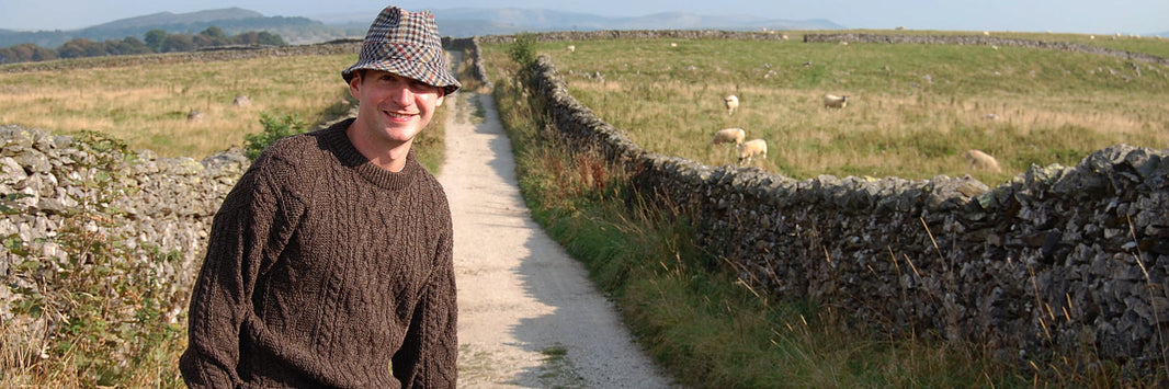 Male model in countryside wearing wool jumper and tweed hat