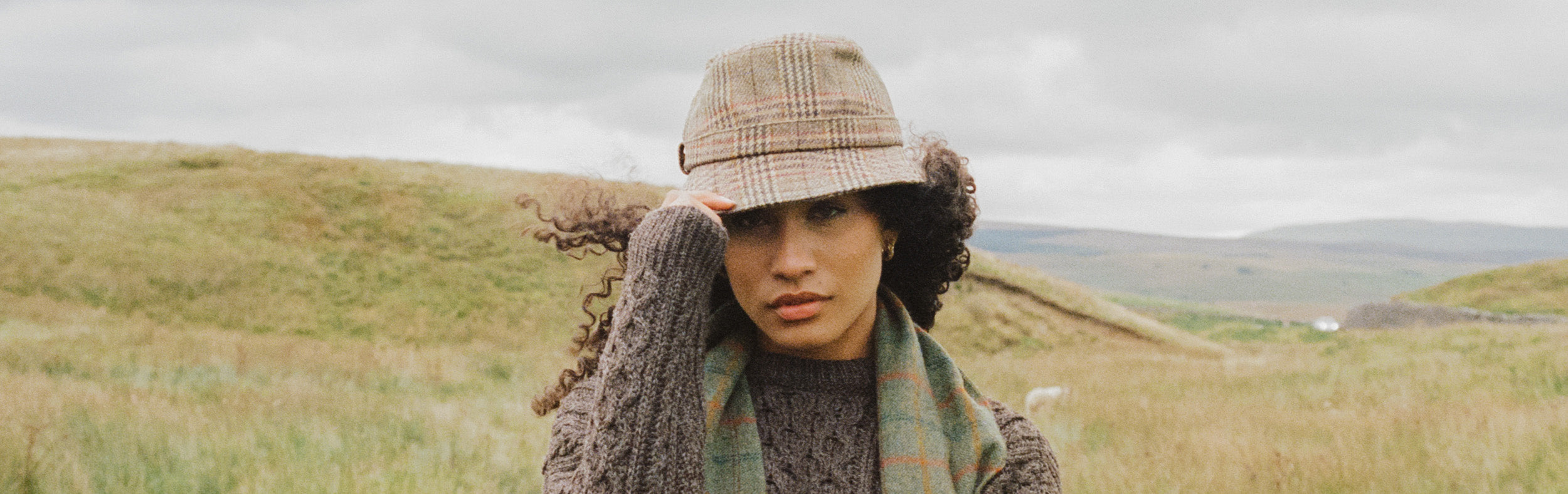 Woman in a field wearing a brown tweed hat