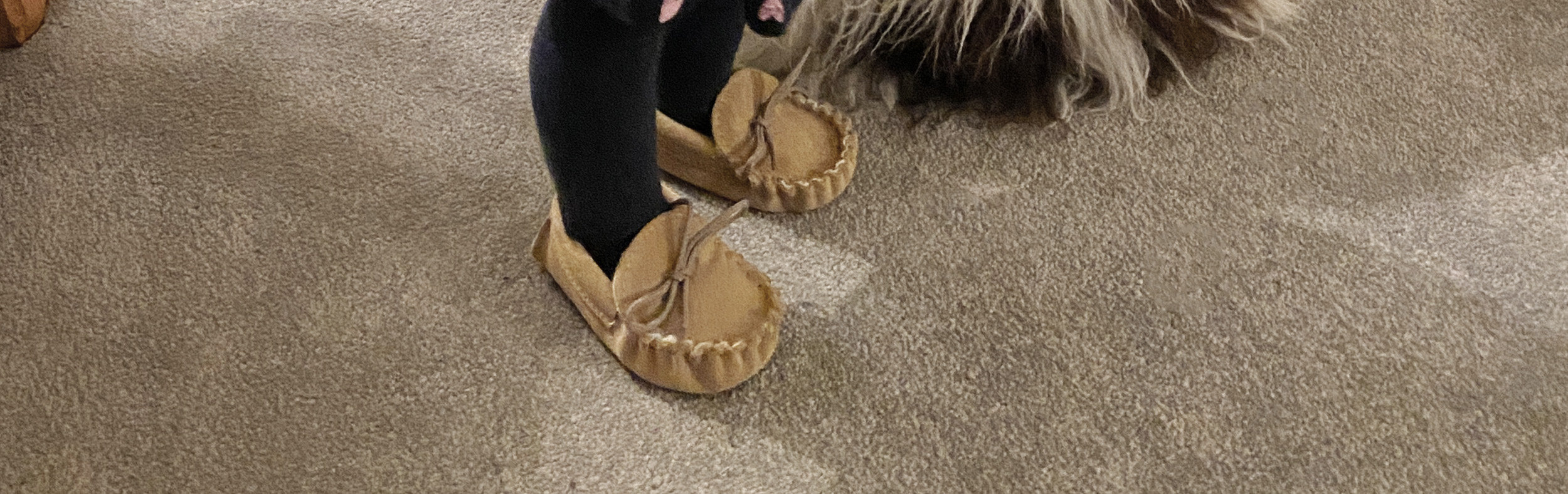 Close up of a child's feet wearing beige suede moccasins