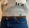 Person wearing a wool jumper, jeans, and a brown leather belt.