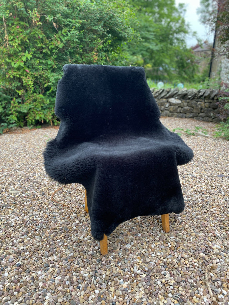 Black short haired sheepskin rug on chair