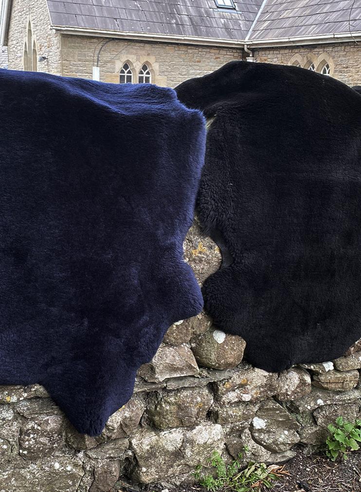 Navy and black short haired sheepskin rugs on wall 