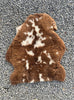 Brown and cream sheepskin rug on gravel