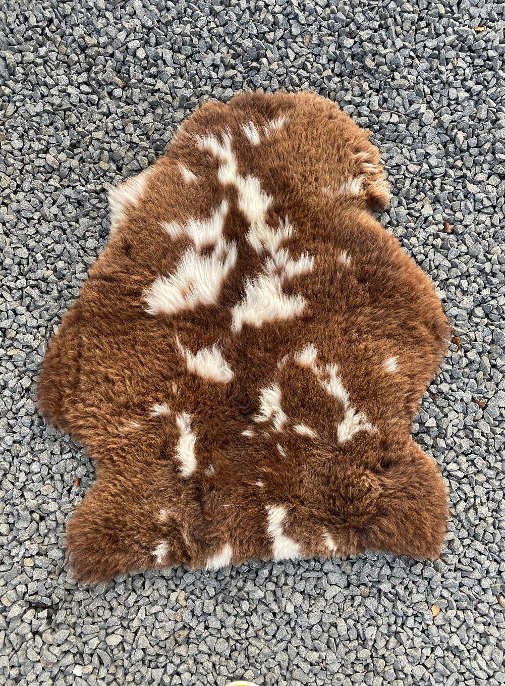 Brown and cream sheepskin rug on gravel