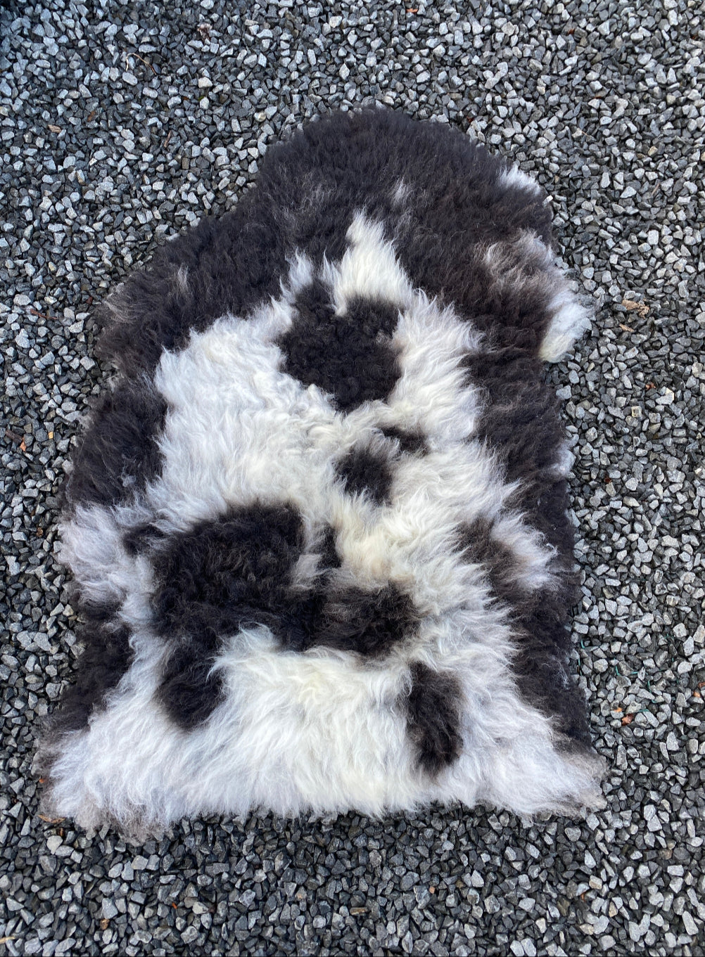 Black and grey sheepskin rug on gravel