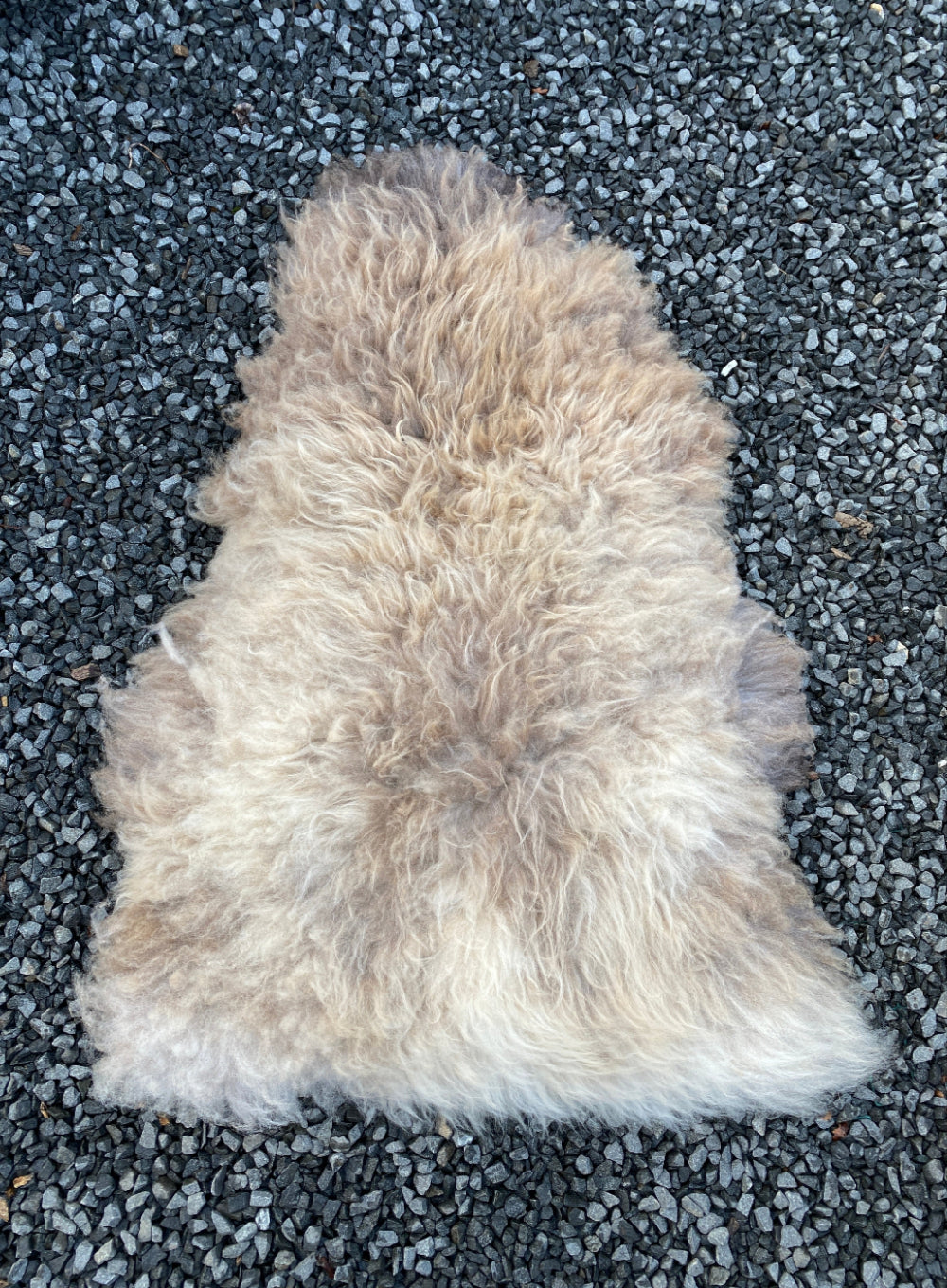 Brown sheepskin rug on gravel