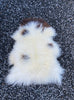 Cream and brown sheepskin rug on gravel