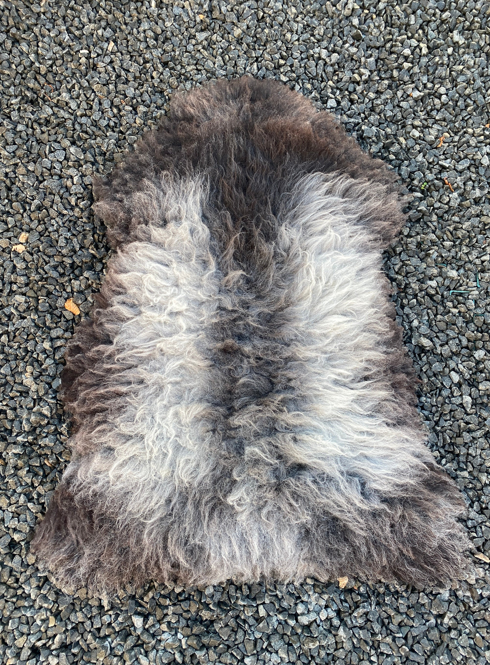 Grey sheepskin rug on gravel 