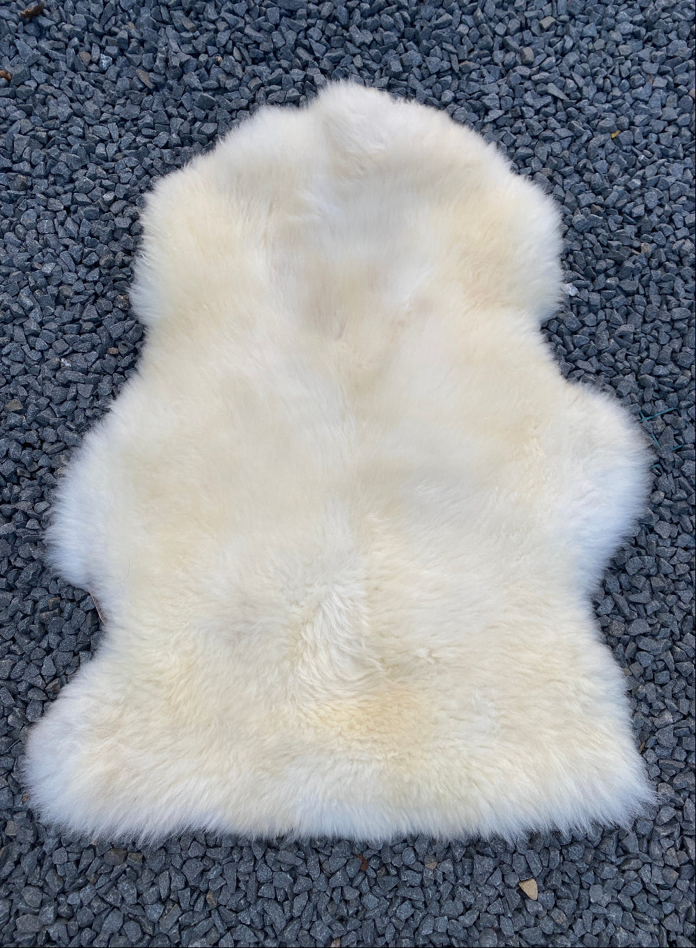 cream sheepskin rug on gravel 