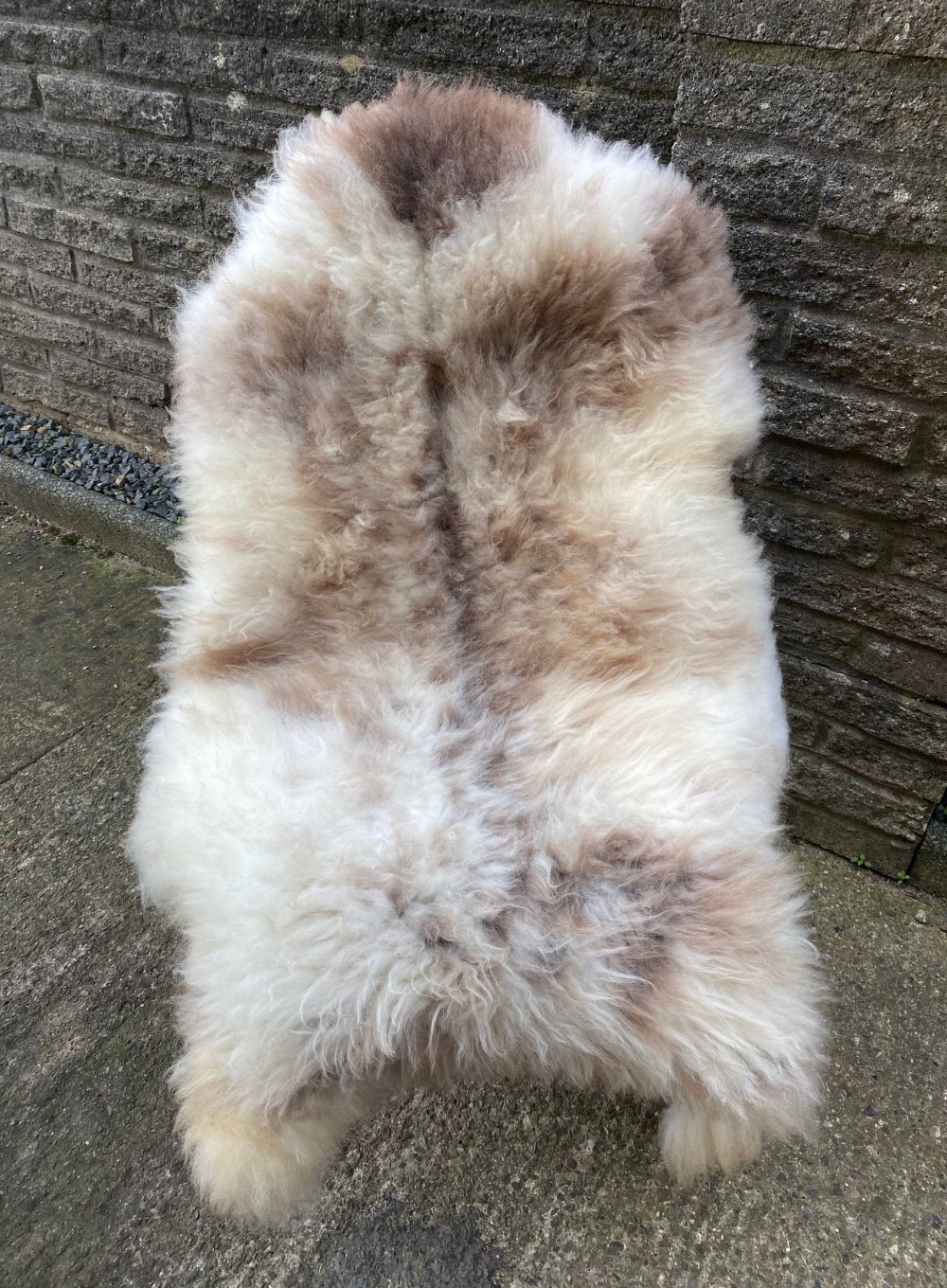 Cream and brown speckled sheepskin rug on chair 