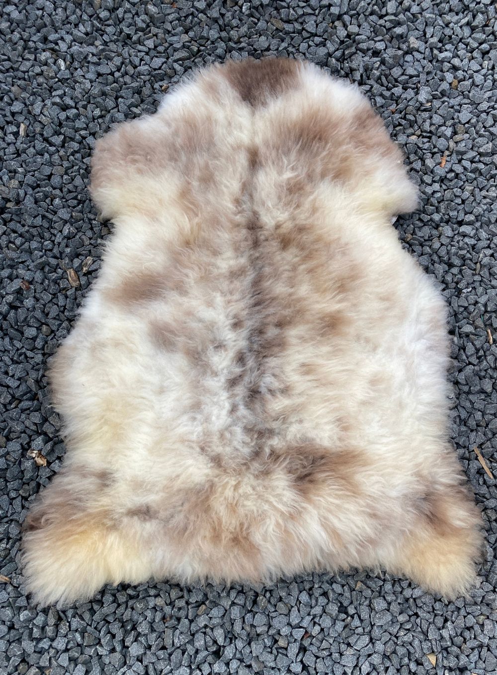 Cream and brown speckled sheepskin rug laid flat