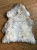Cream speckled sheepskin rug on wooden floor 