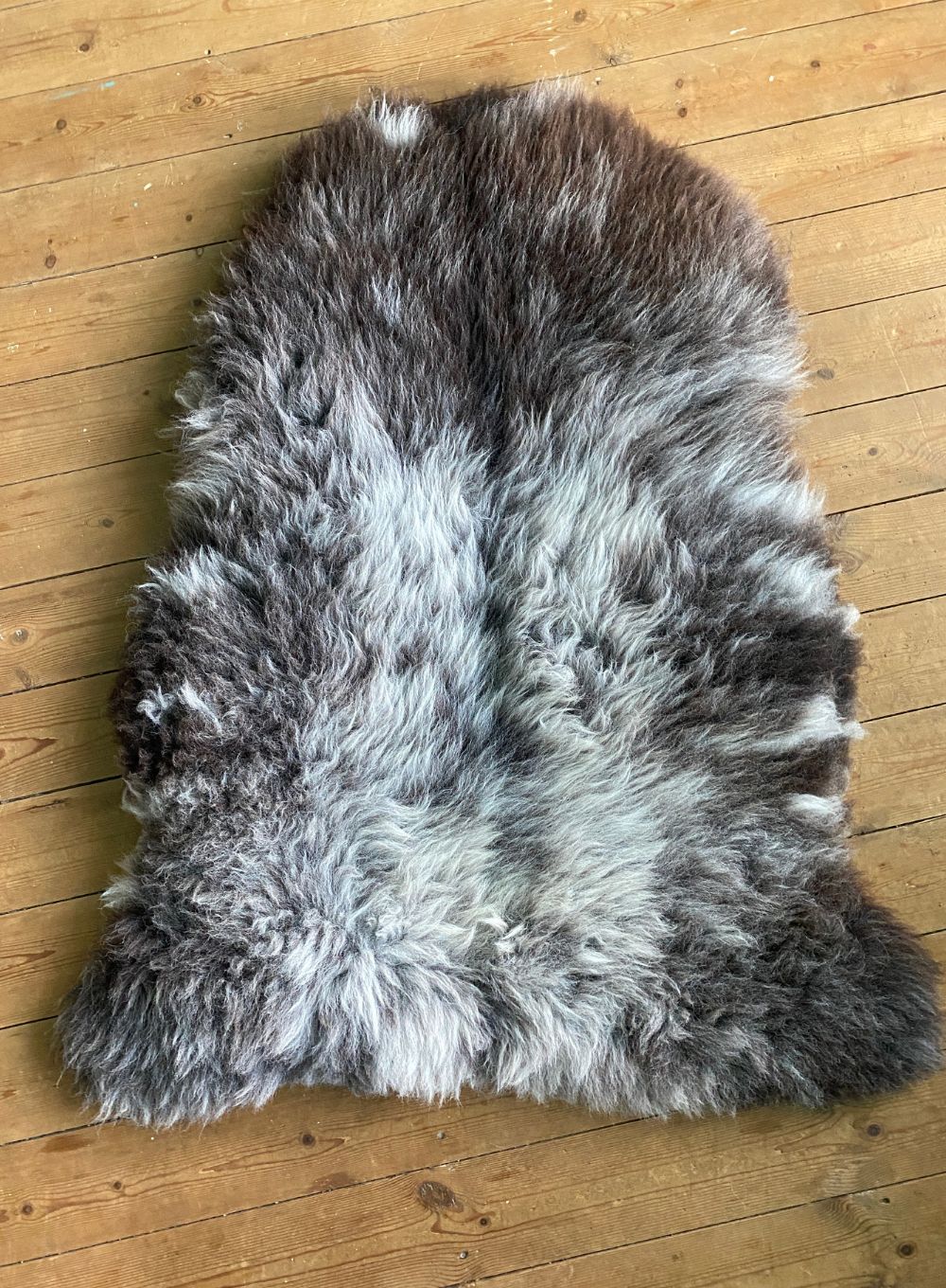 Brown and grey sheepskin rug on wooden floor