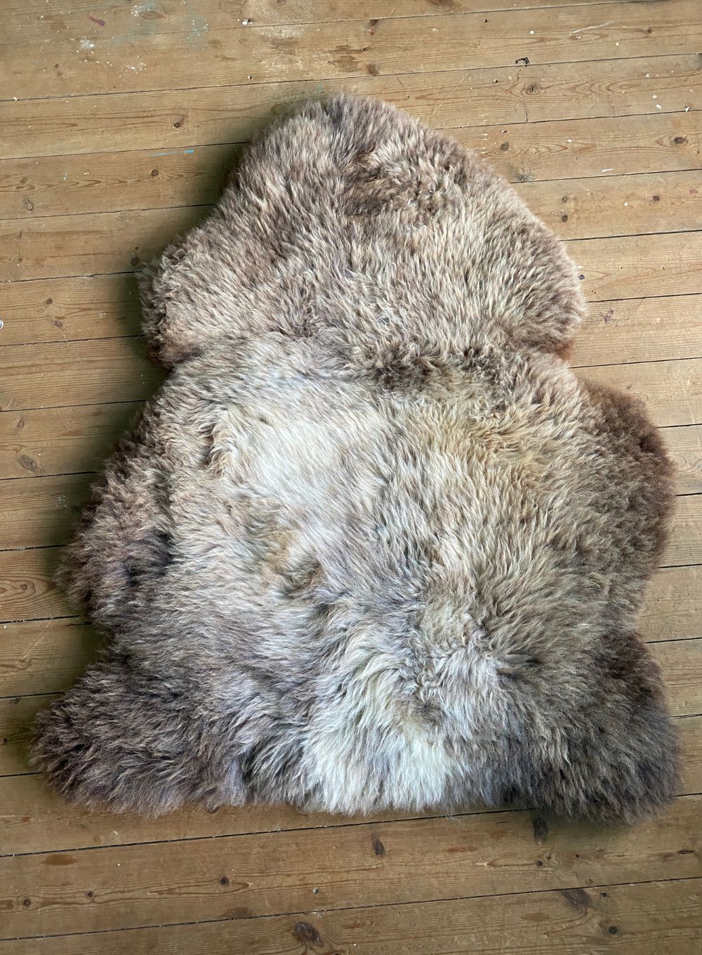 Brown and cream sheepskin rug  laid flat on wooden floor