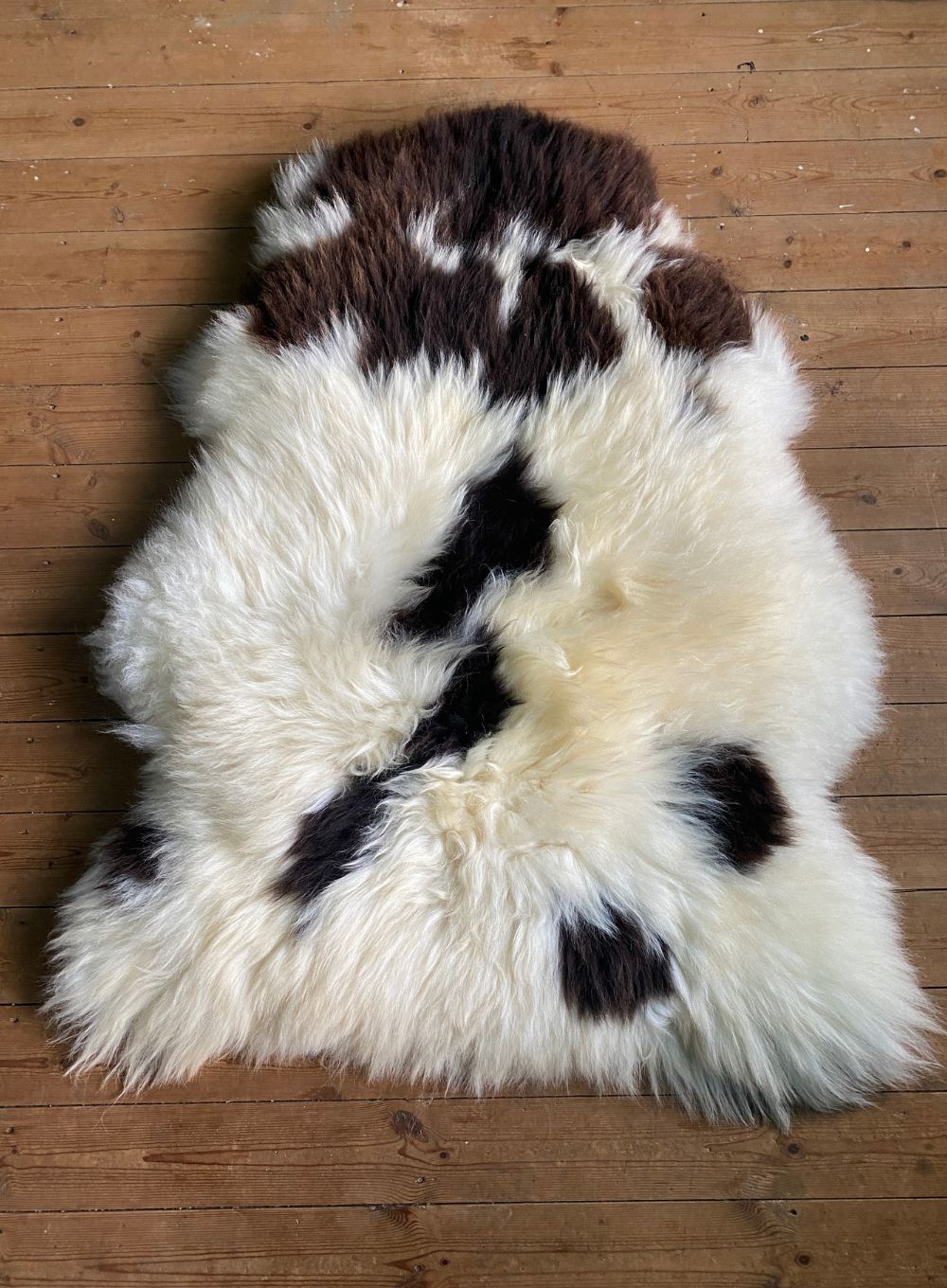 Brown and crem sheepskin rug flat on wooden floor 