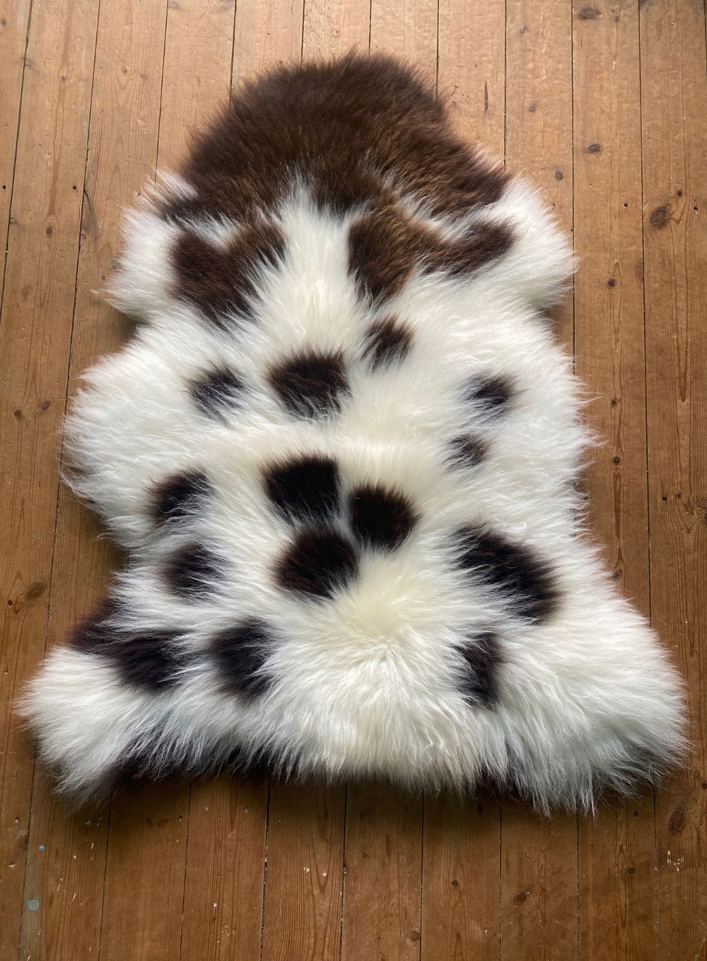 Cream and brown sheepskin rug laid flat on wooden floor