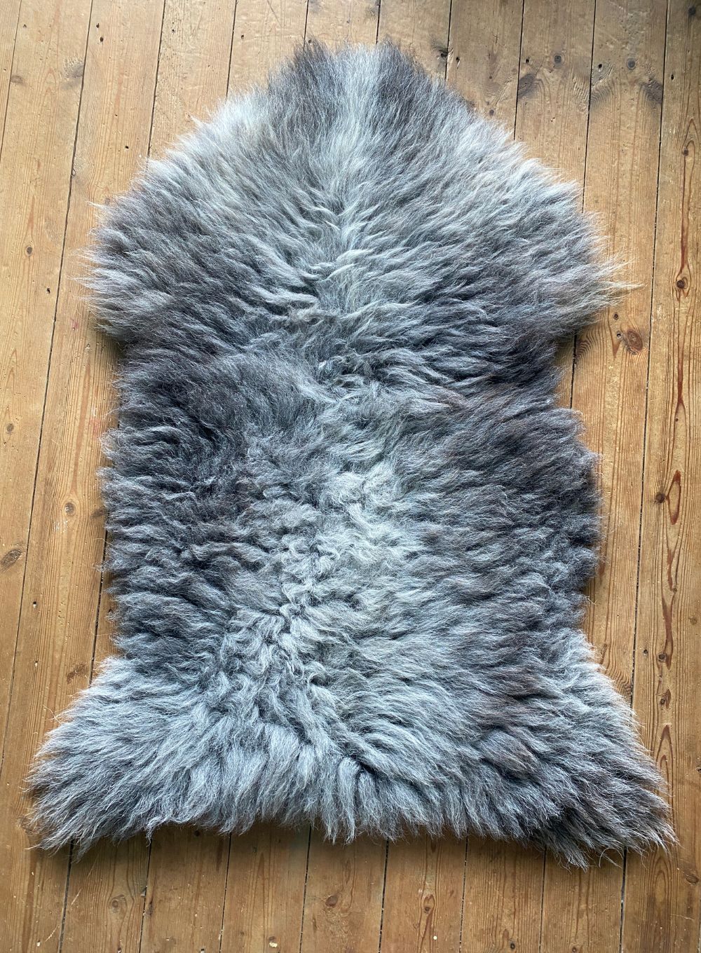 Grey sheepskin rug laid flat