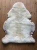 Cream sheepskin rug laid flat on wooden floor