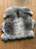 Grey sheepskin rug laid flat on wooden floor 
