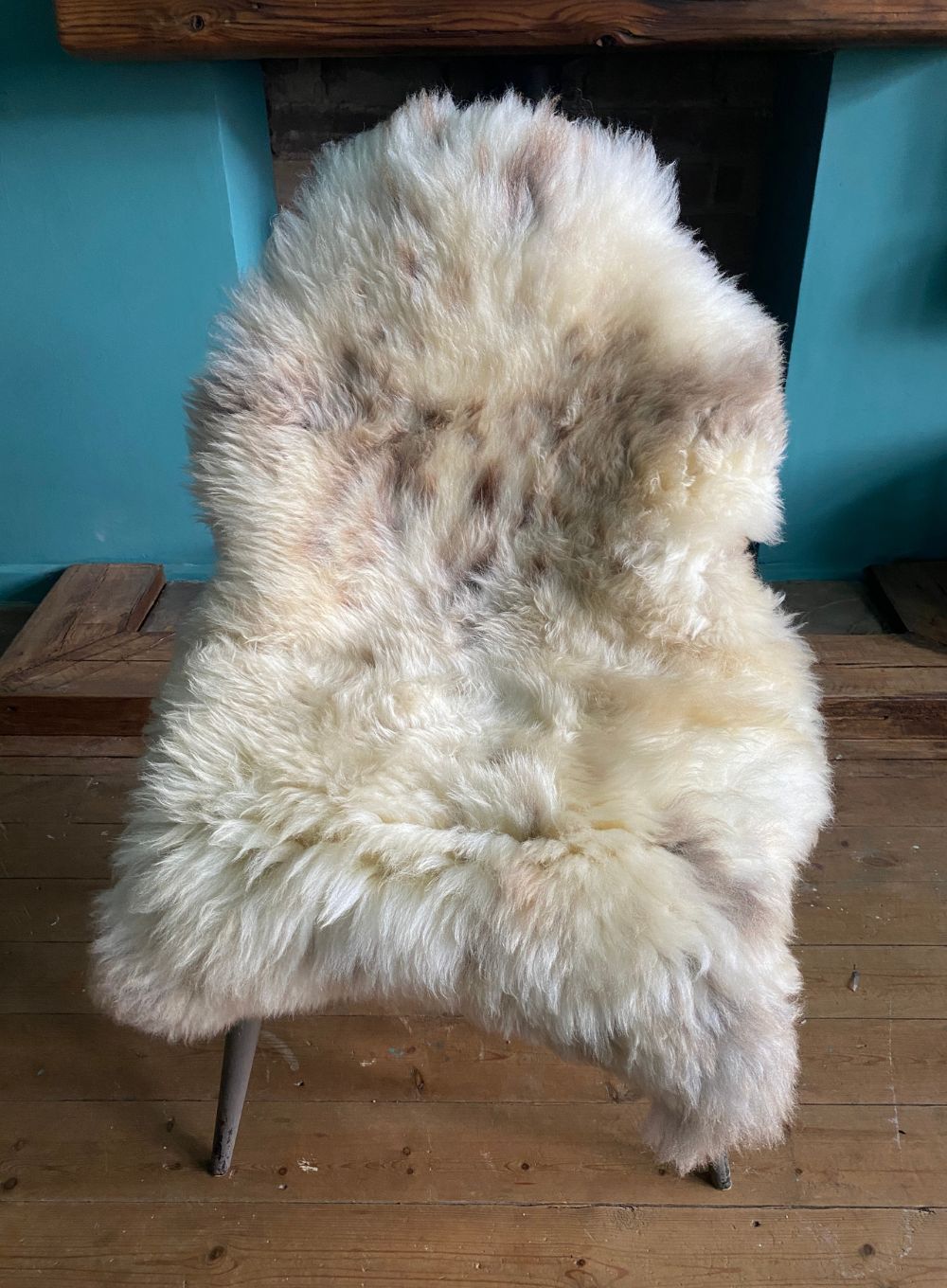 Cream speckled sheepskin rug on chair 