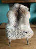 Brown and grey sheepskin rug on chair 