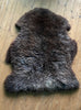 Brown sheepskin rug laid flat on wooden floor 
