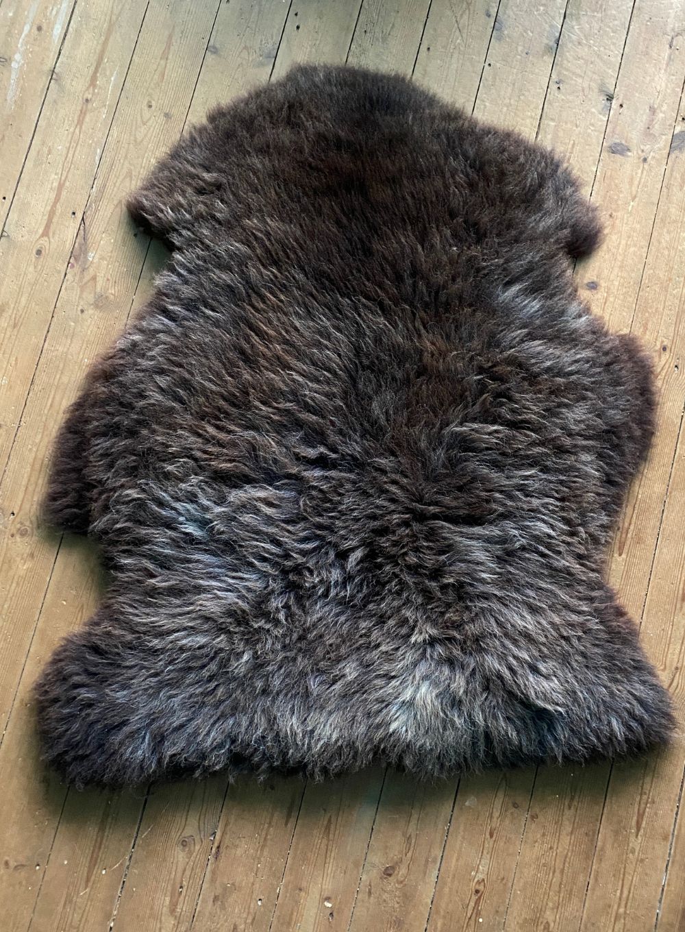 Brown sheepskin rug laid flat on wooden floor 