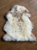Cream speckled sheepskin rug on wooden floor