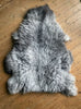 Grey sheepskin rug on wooden floor