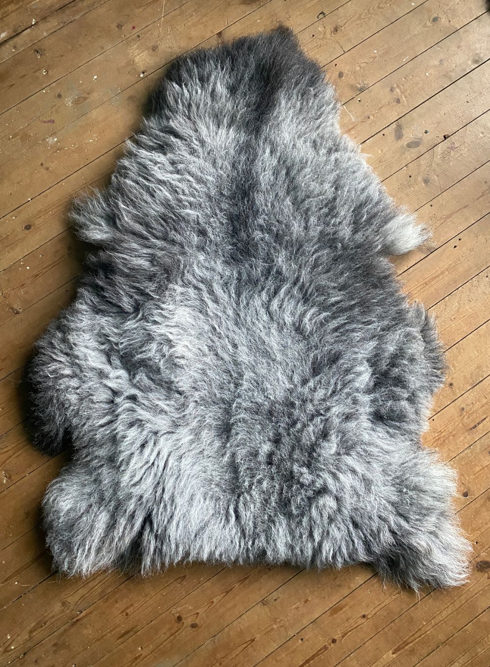 Grey sheepskin rug on wooden floor