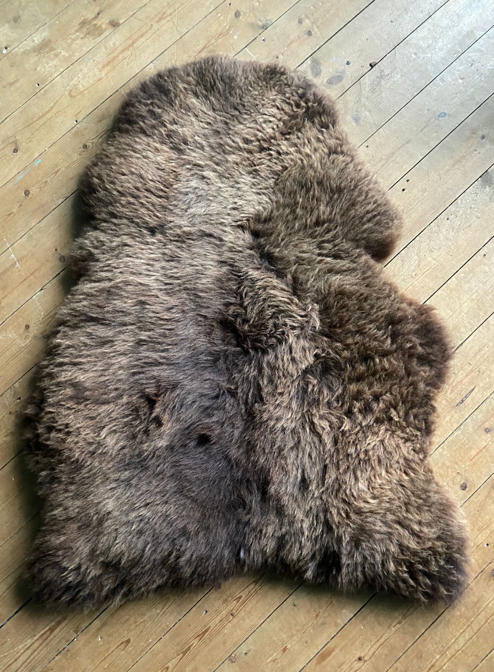 Brown sheepskin rug on wooden floor 