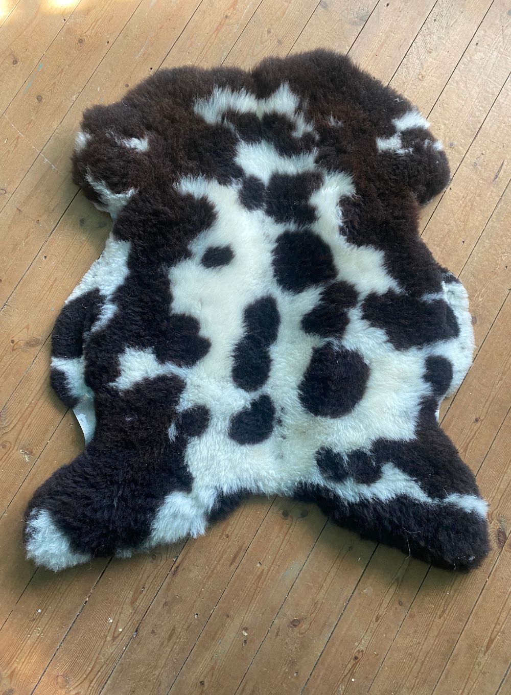 Brown and cream sheepskin rug on wooden floor 