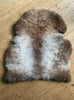 Brown and cream sheepskin rug on wooden floor 