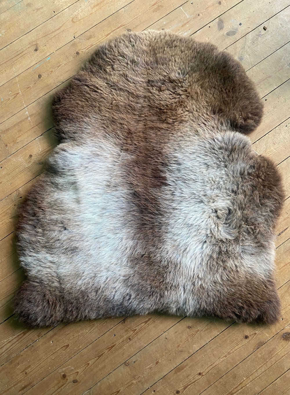 Brown and cream sheepskin rug on wooden floor 
