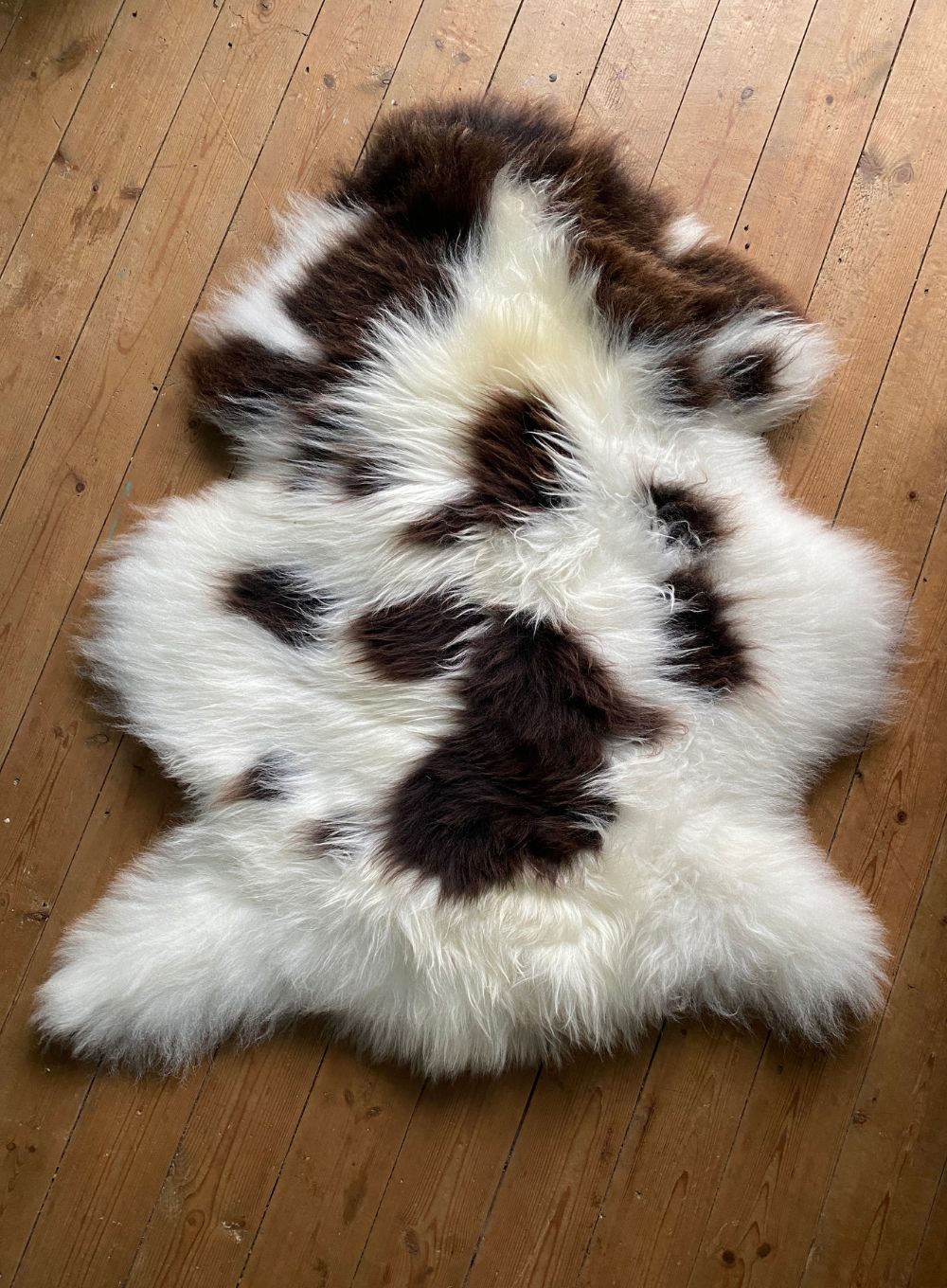 Brown and cream sheepskin rug on wooden floor 