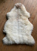 Cream speckled sheepskin rug on wooden floor