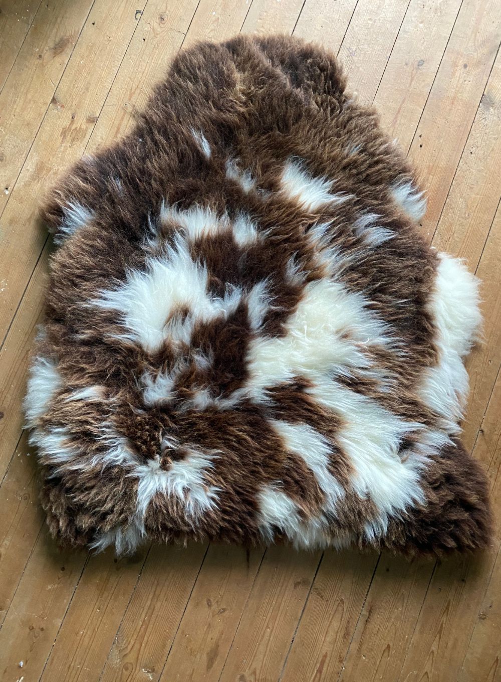 Brown and cream sheepskin rug on wooden floor