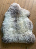 Cream speckled sheepskin rug on wooden floor