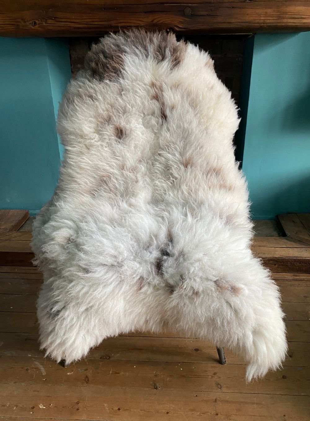 Cream and brown speckled sheepskin rug on chair