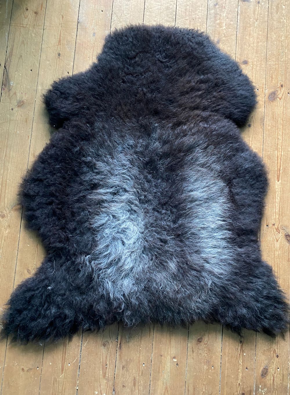 Dark brown sheepskin rug on wooden floor