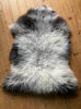 Grey sheepskin rug on wooden floor 