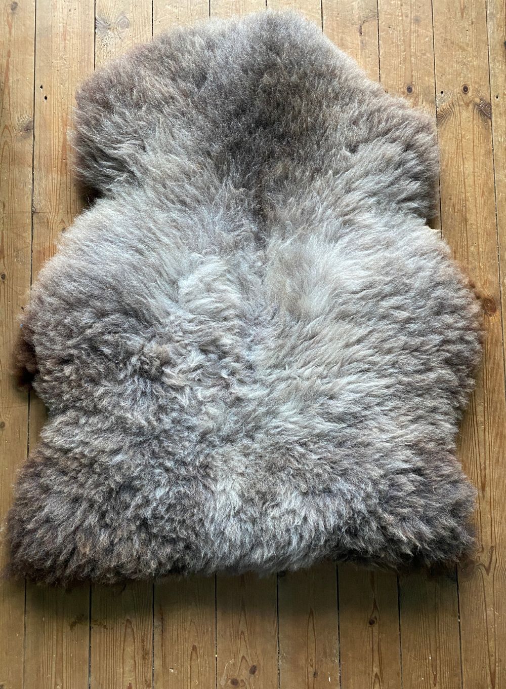 Brown and grey sheepskin rug on wooden floor