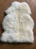 Cream sheepskin rug on wooden floor