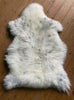 Cream speckled sheepskin rug on wooden floor