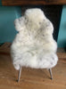 Cream speckled sheepskin rug on chair 