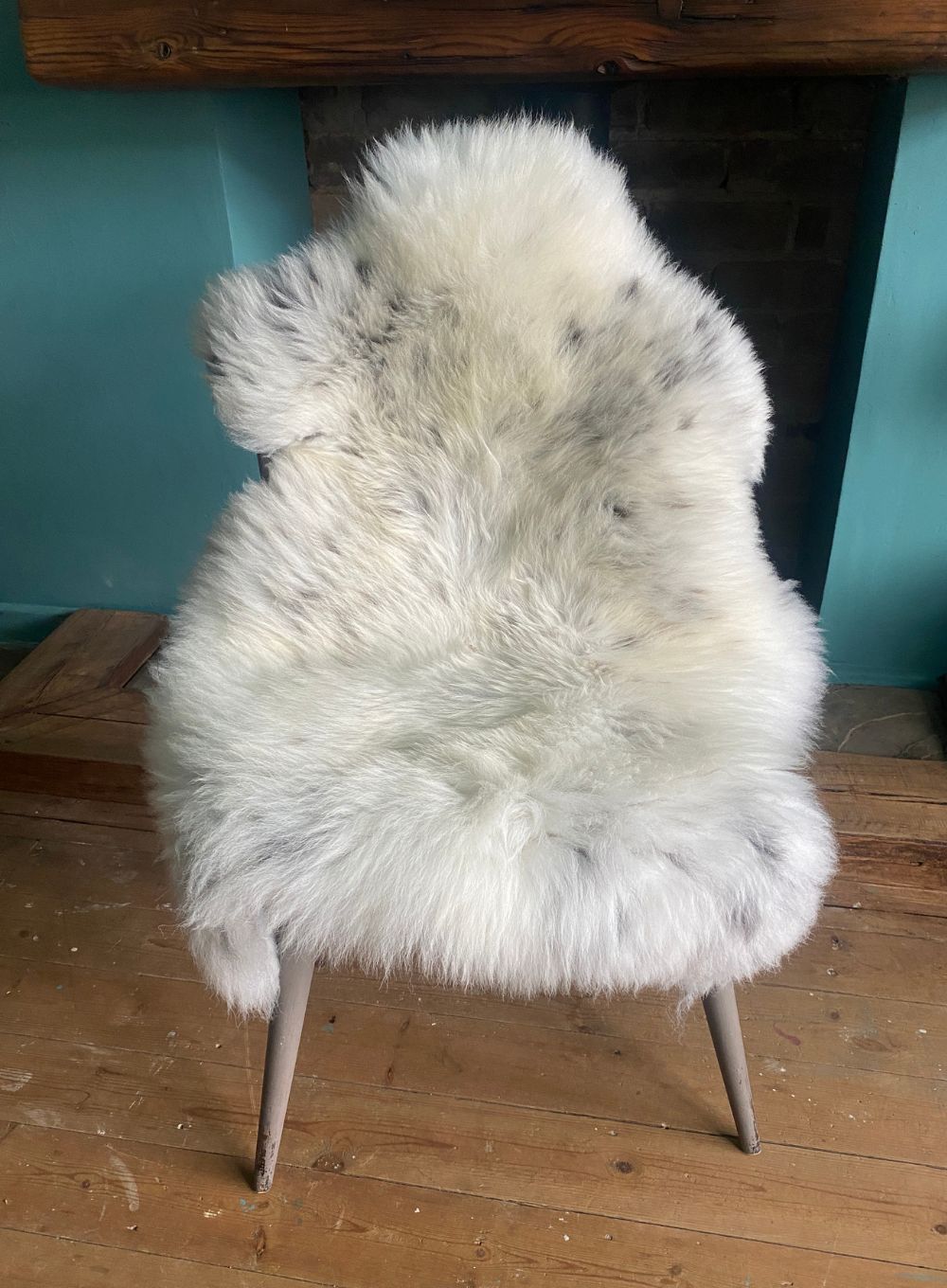 Cream speckled sheepskin rug on chair 