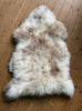 Cream speckled sheepskin rug on wooden floor 