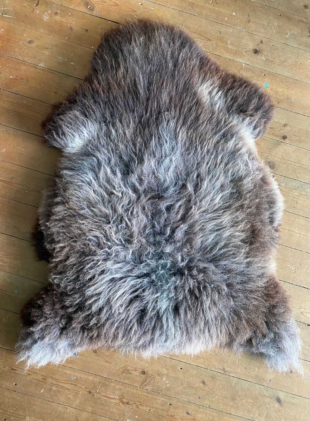 Brown and grey sheepskin rug on wooden floor
